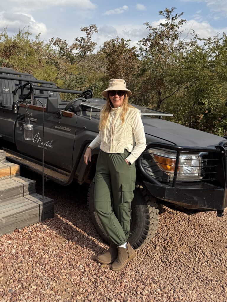 Travel advisor posing beside a luxury safari vehicle before a South Africa family adventure.
